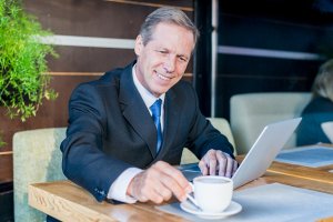 happy businessman having cup coffee with laptop desk caf